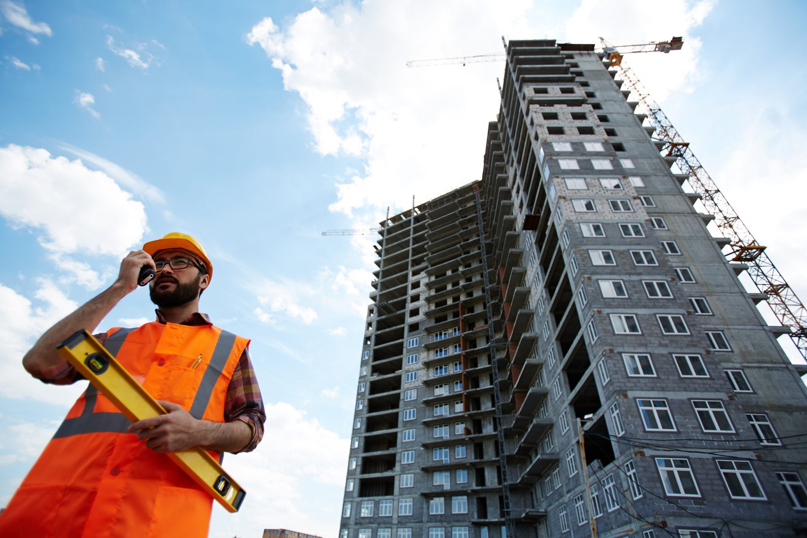 Contractor in uniform speaking on walkie-talkie by unfinished building